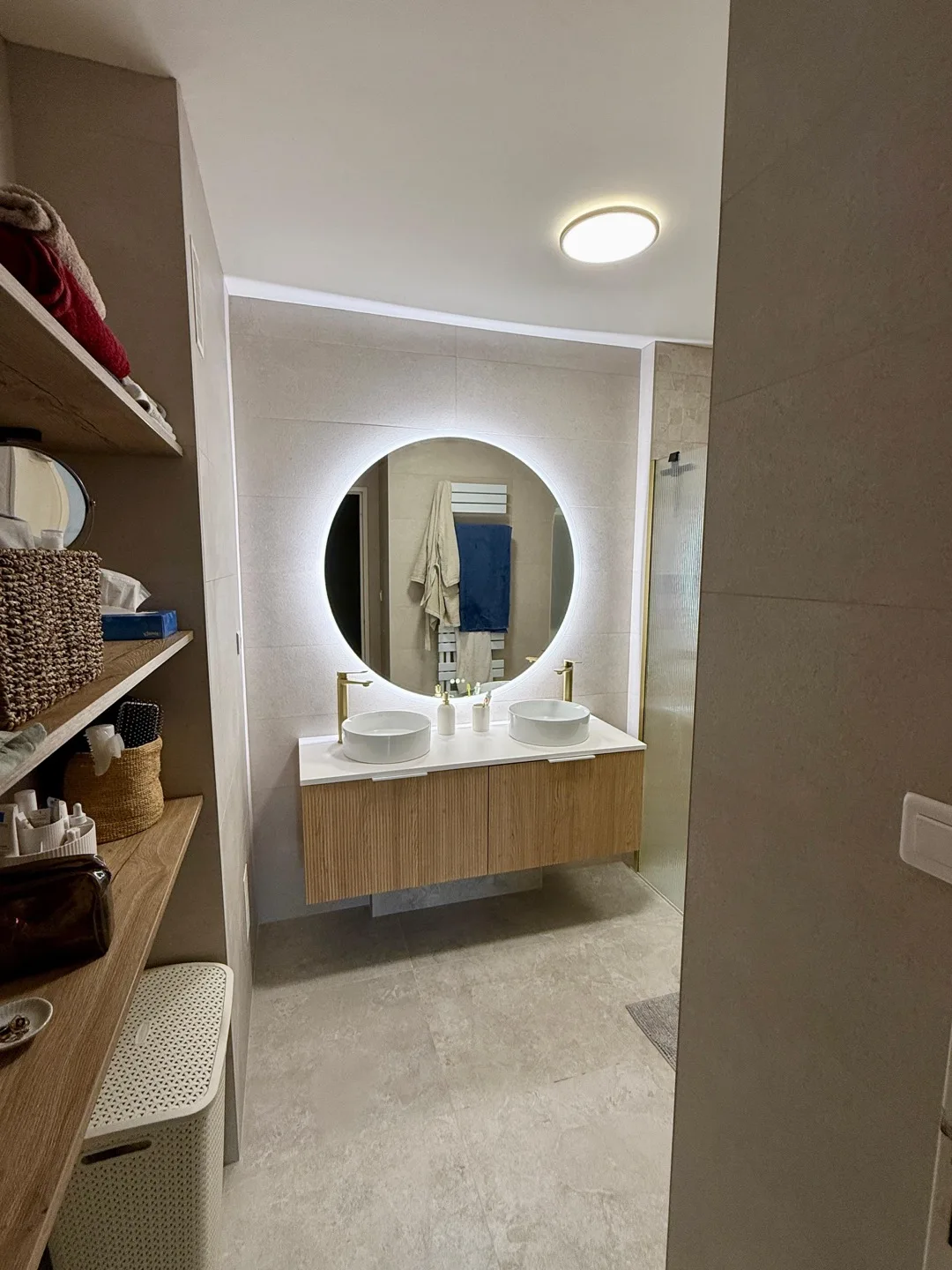 Meuble vasque et miroir rond dans une salle de bain rénovée par VALEX