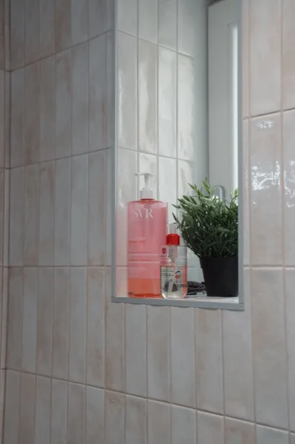 Niche murale intégrée dans le carrelage clair de la douche